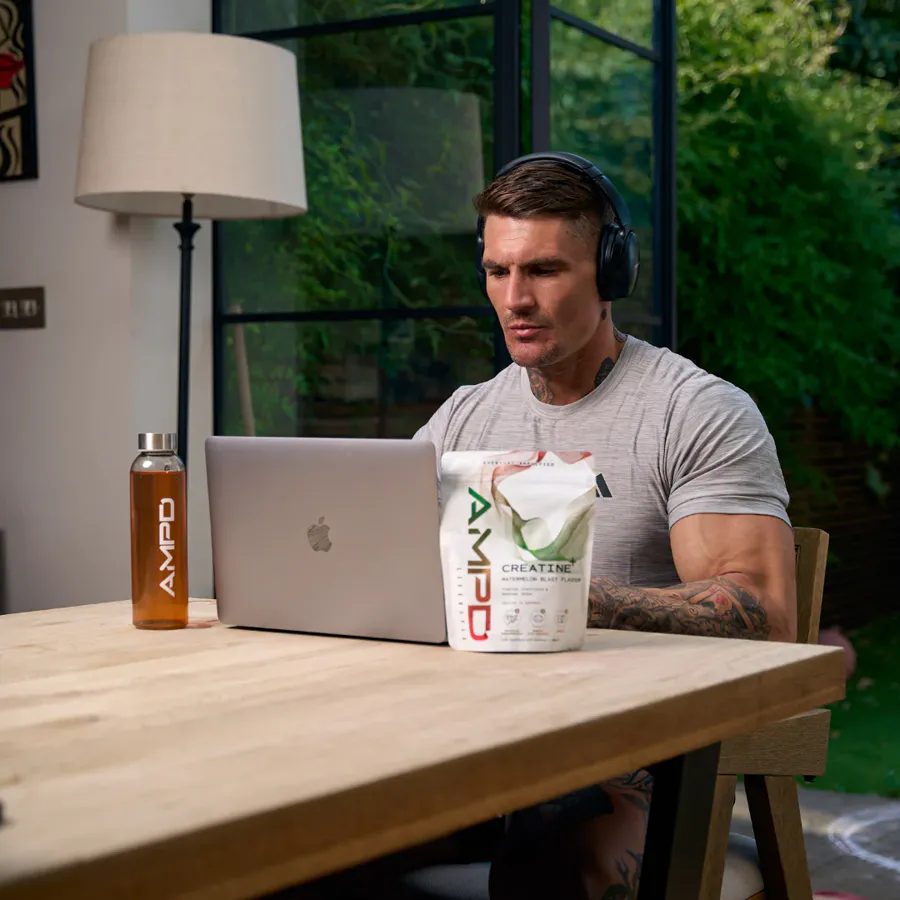 Ross working at a laptop with headphones on, AMPD Creatine+ beside him