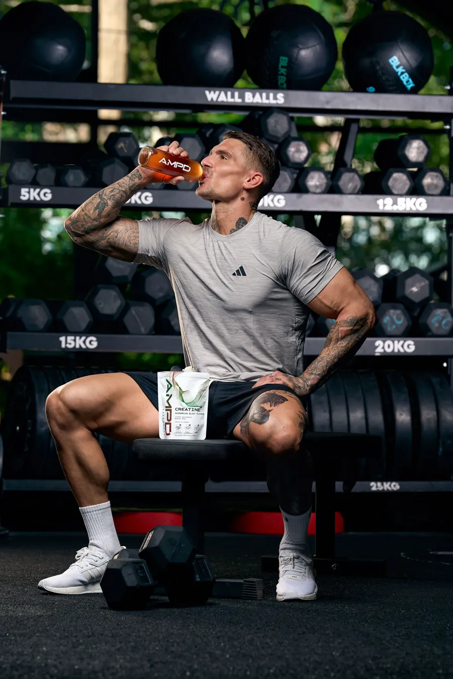Ross drinking AMPD on a gym bench with the Creatine+ pouch on his knee